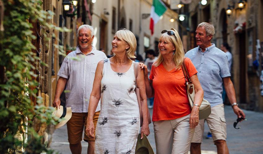 A group of mature travellers walking down a street in Italy.