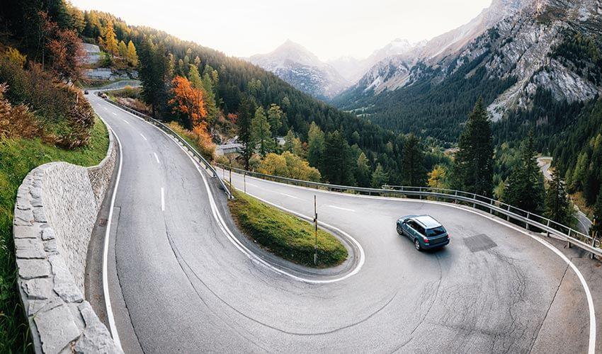 A car driving down a curvy road in the mountains.