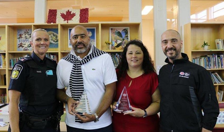 A group of people standing in front of a bookshelf with a canadian police officer.