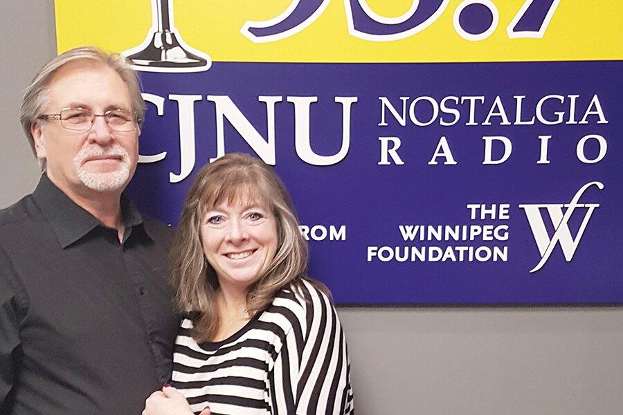 A man and woman standing in front of a cnu radio sign.