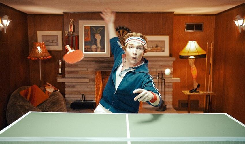 A man playing ping pong in a living room.