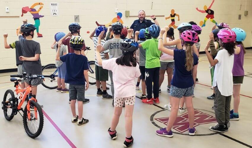 A group of children wearing helmets in a gymnasium.