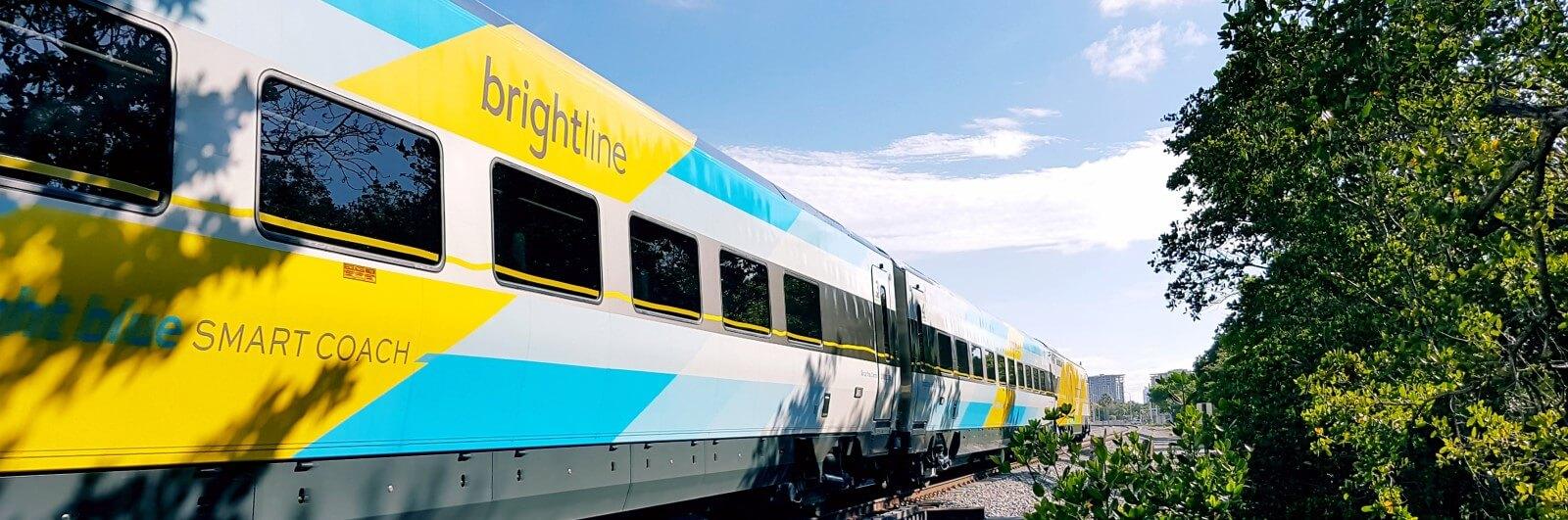 A yellow and blue train is traveling down the tracks.